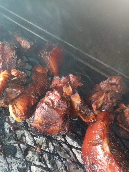 Smoky grilled meat pieces on a barbecue grill with a charred texture.